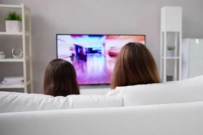 Mor og datter sitter i sofaen og ser på tv