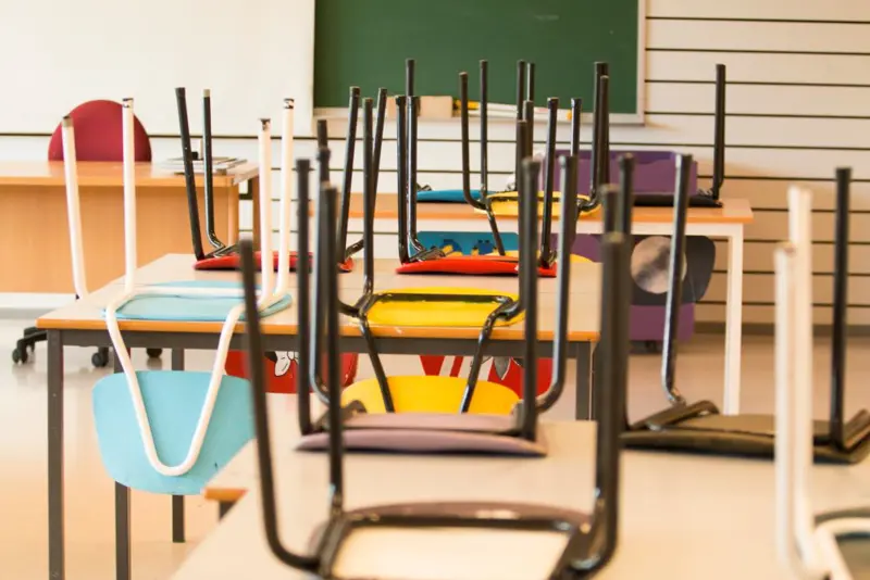 stoler som er satt opp på pulter i et tomt klasserom