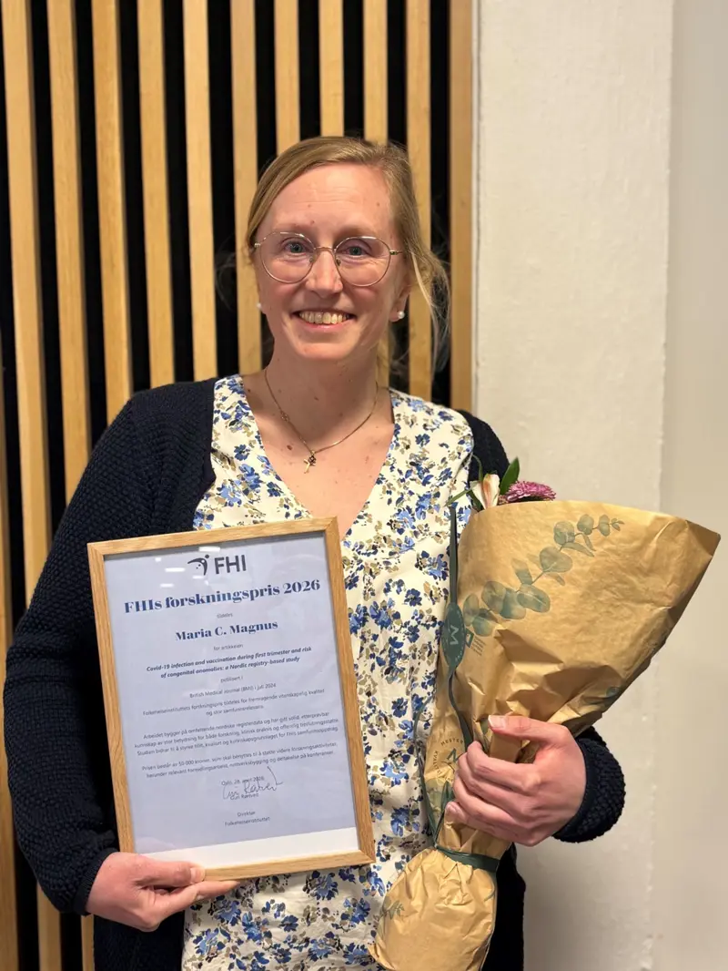 En dame (Maria Magnus) som smiler i kamera mens hun holder en blomst og en pris i hånda