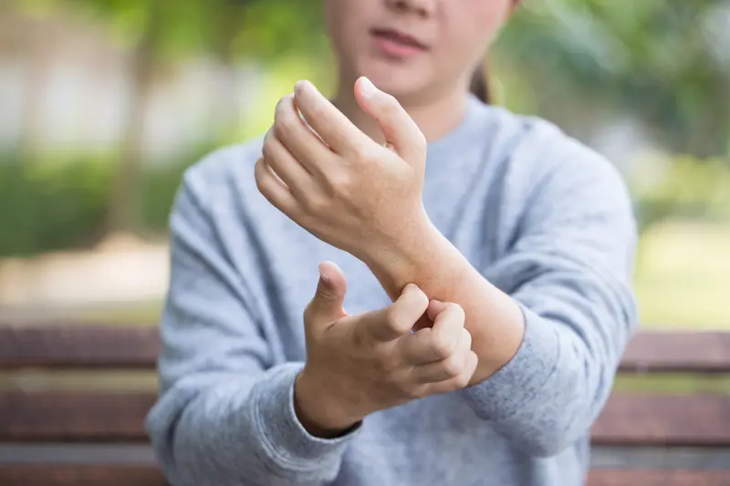 Kvinne som klør på underarmen eller håndledd. Woman scratching her skin.