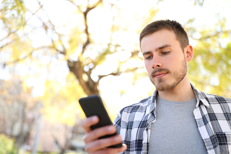 illustrasjonsfoto av en ung mann som ser på mobiltelefonen