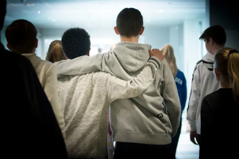 To gutter går gjennom en skolekorridor mens de holder hverandre over skulderen