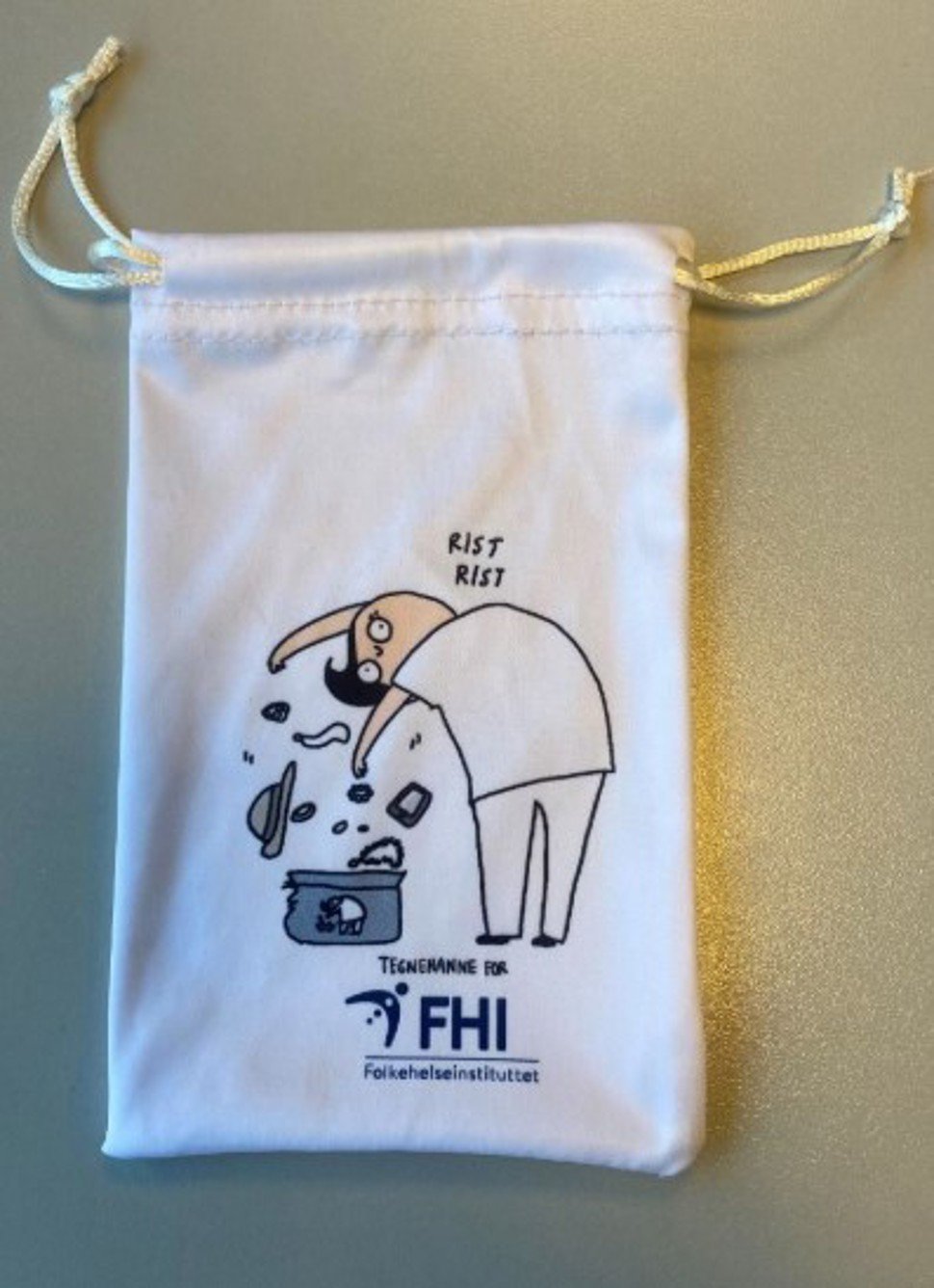 Bilde av smykkepose med Tegnehanne+FHI-logo og Tegnehanne-illustrasjon av helsearbeider som rister smykker o.l. av seg og ned i smykkepose