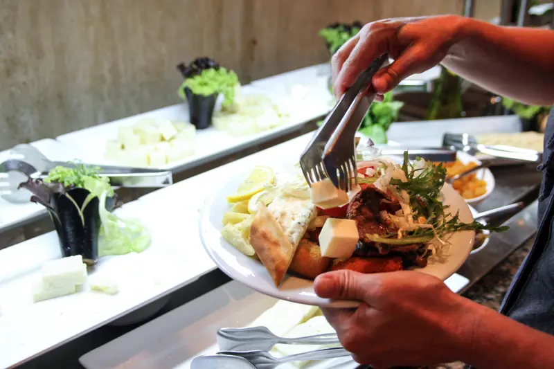 En person legger mat på en tallerken.