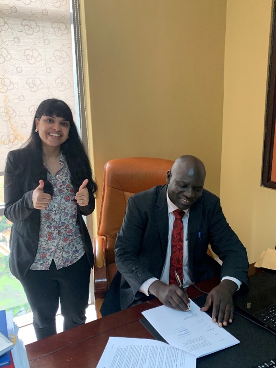 Photo 1: BIS Uganda Country Coordinator Mahima Venkateswaran looks on as Dr Alex Ario Riolexus, Director of UNIPH, signs the Collaboration Agreement