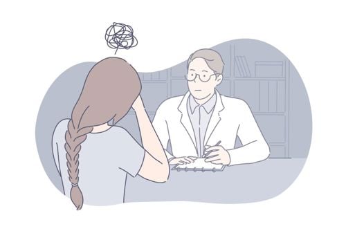 En kvinne som tar seg til hodet mens hun snakker med doktoren