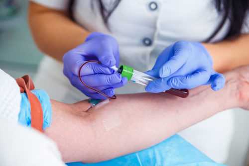 En helsesykepleier tar blodprøve fra armen til en pasient