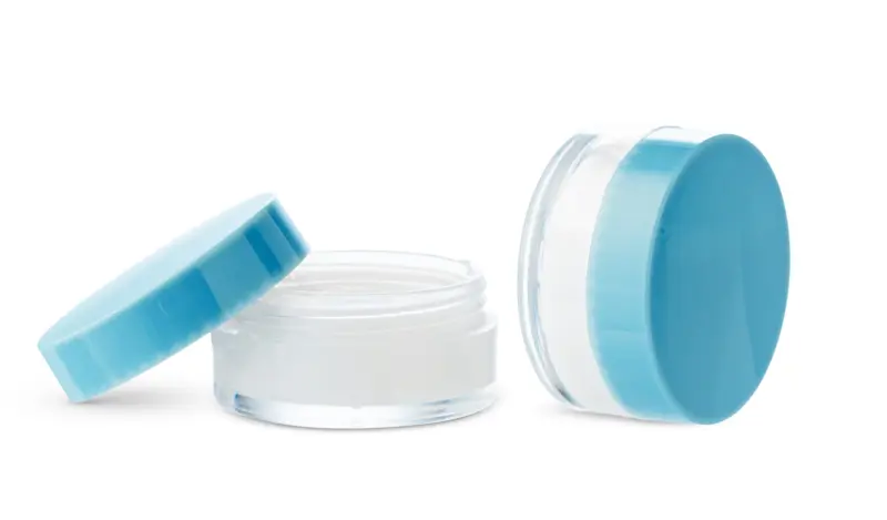 Open cosmetic jars showcasing different creams set. Sett med to åpne bokser med kremer.