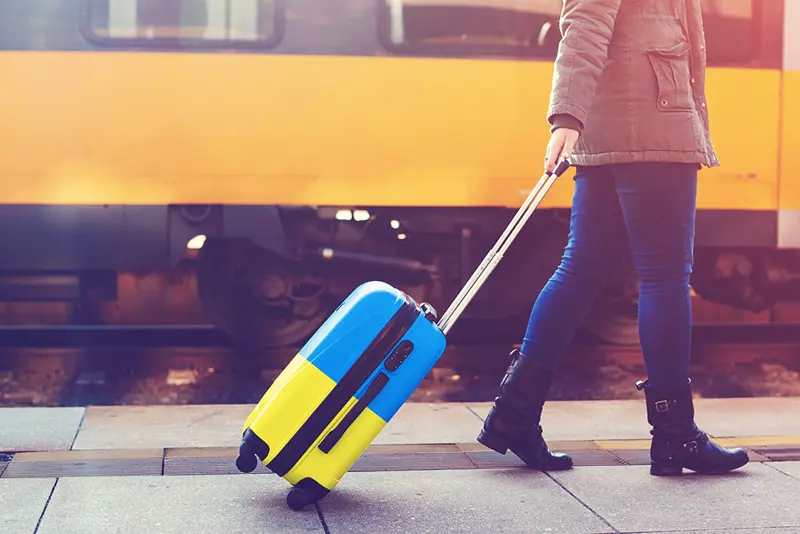 Bilde av kvinne med koffert i det ukrainske flaggets farger