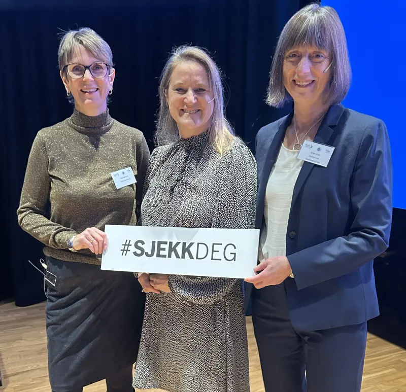 Tre kvinner som holder et skilt