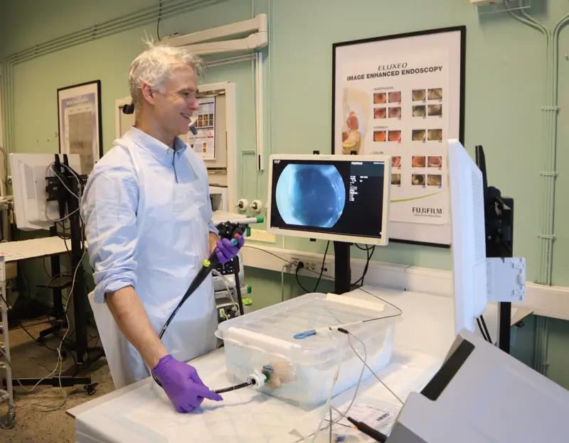 Mann holder en endoskop og ser på to skjermer