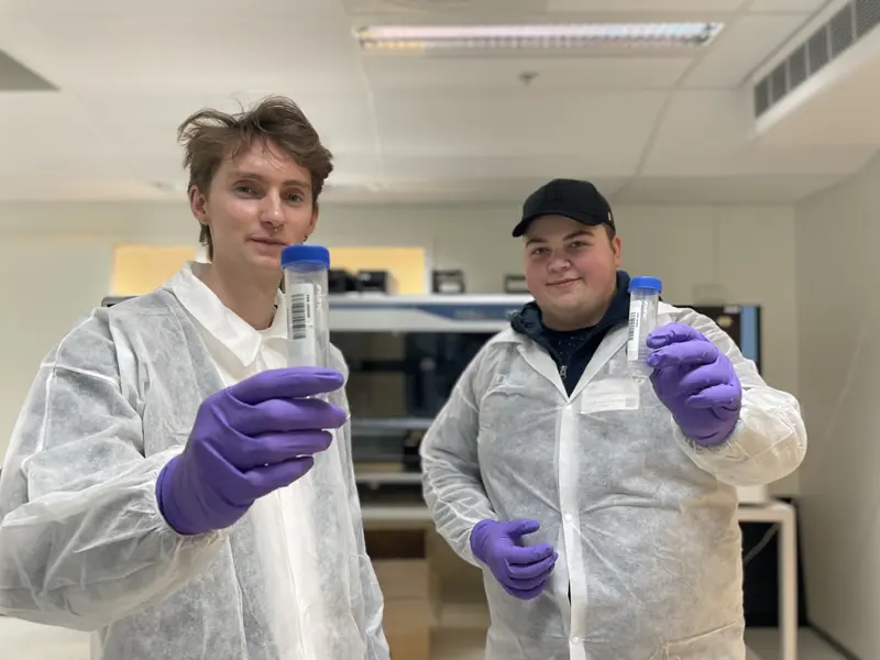 Bilde av to gutter som er intervjuet i saken som holder frem et reagensrør