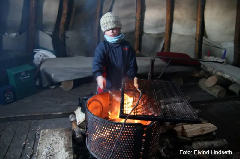 barn som griller pølse inne i lavvo