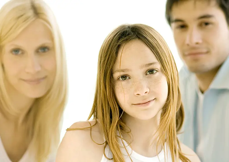jente med foreldre i bakgrunnen