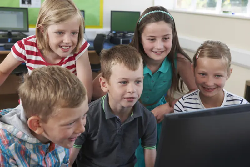 barn som står sammen og ser på en datamaskin