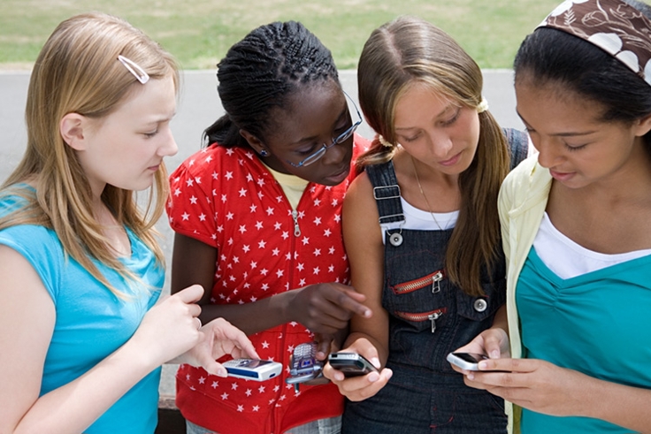 unge jenter som ser på mobiltelefonen til hverandre