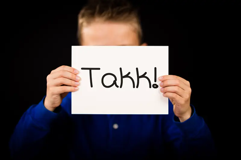 gutt holder opp skilt der det står takk