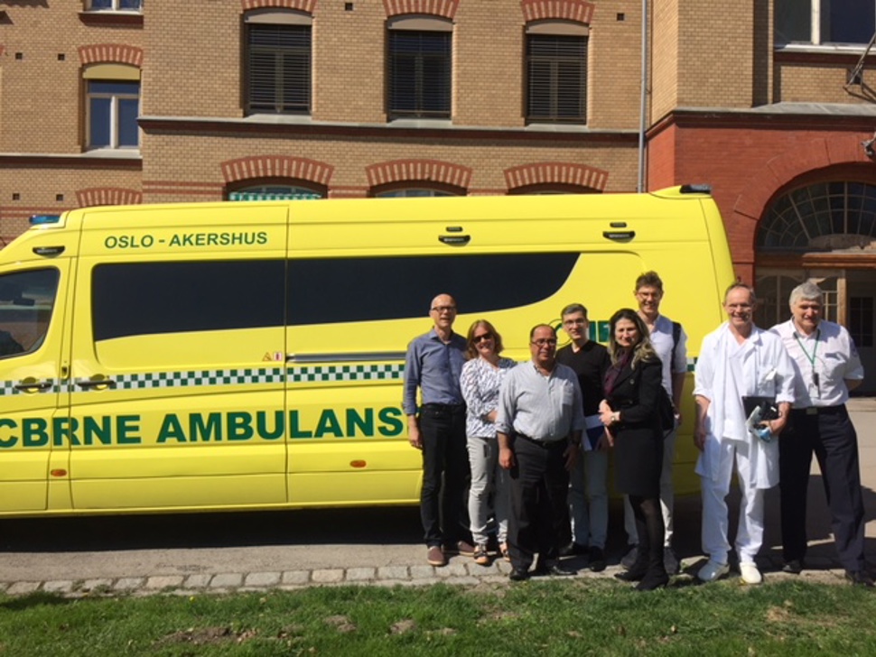 Group of people in front an ambulance car outside a hospital building