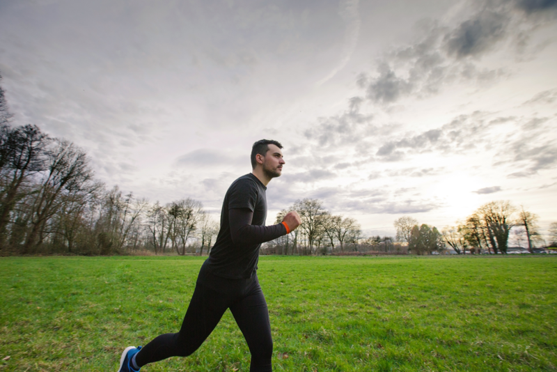 Ung mann som jogger i en park