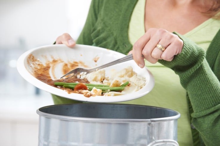 person skraper matrester fra tallerken ned i søpla