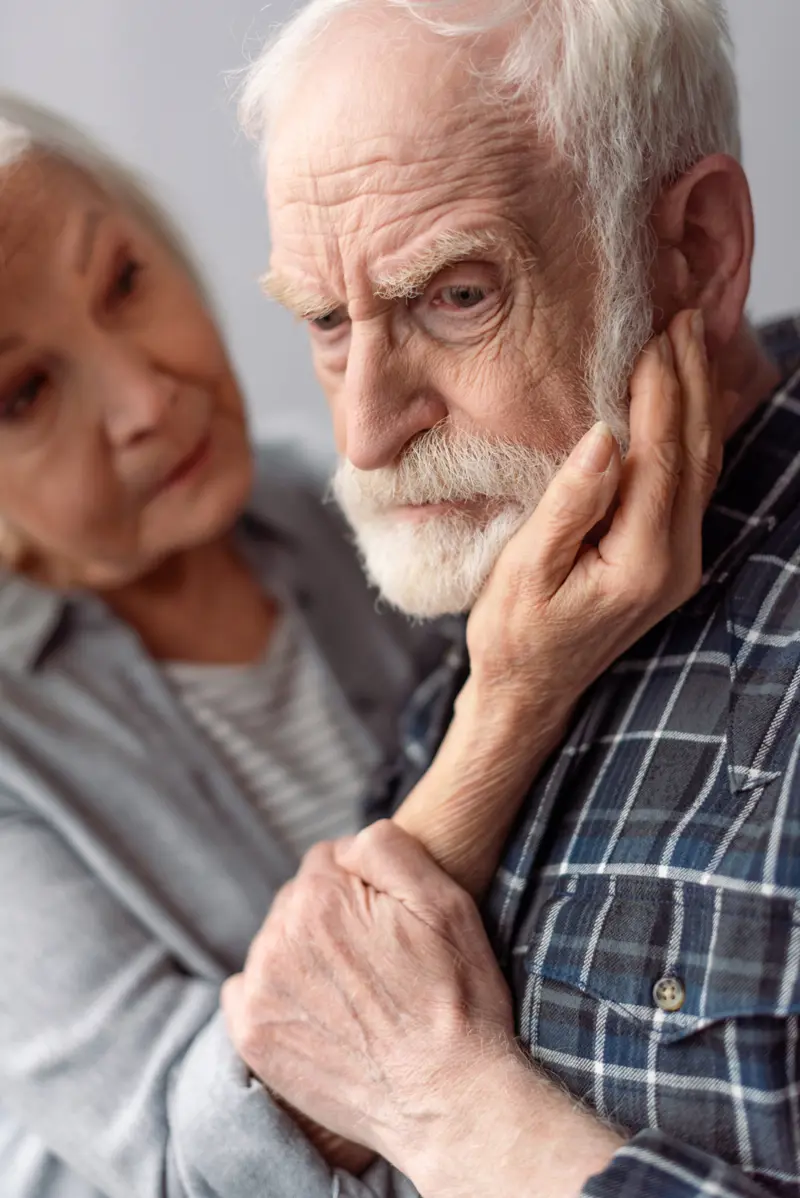 Bilde av eldre ektepar, hun holder rundt hodet hans