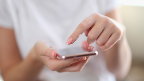 Kvinnehånd som scroller på en mobiltelefon