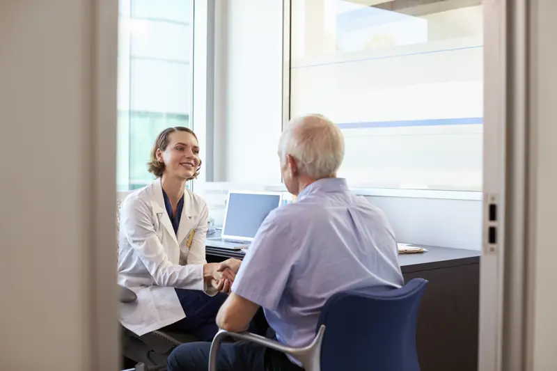 Kvinnelig lege i samtale med eldre pasient.