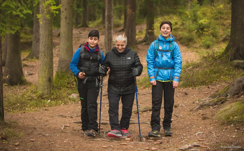To unge gutter og én eldre kvinne ute i naturen