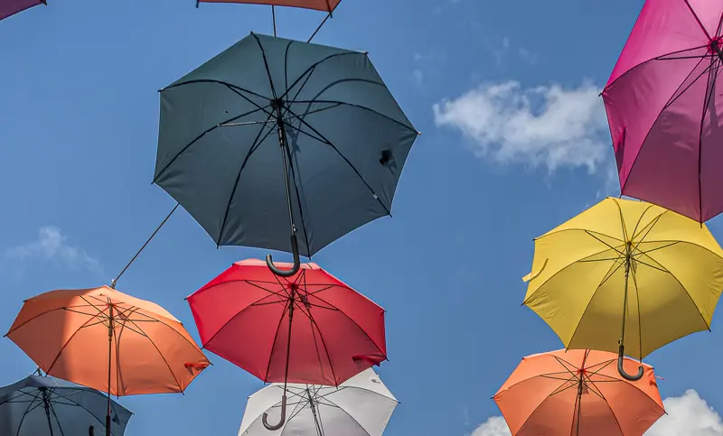 Foto av fargerike paraplyer sett unnenifra i en handlegate