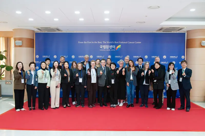 Picture of app. 30 attendants on red carpet and blue background