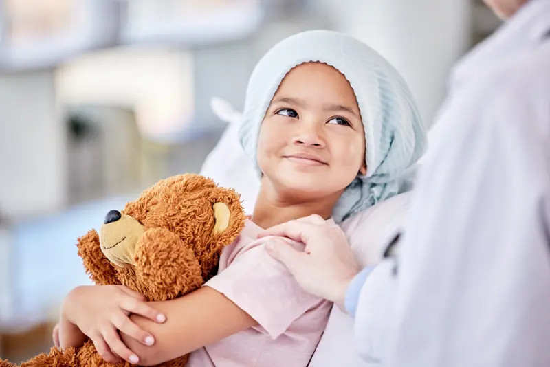 Child in hospital bed with teddy bear