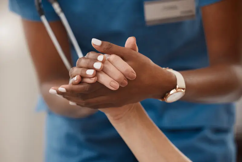 Shot of a doctor holding hands with her patient during a consultation at home