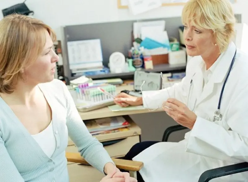 lege som snakker med ung kvinne på legekontor