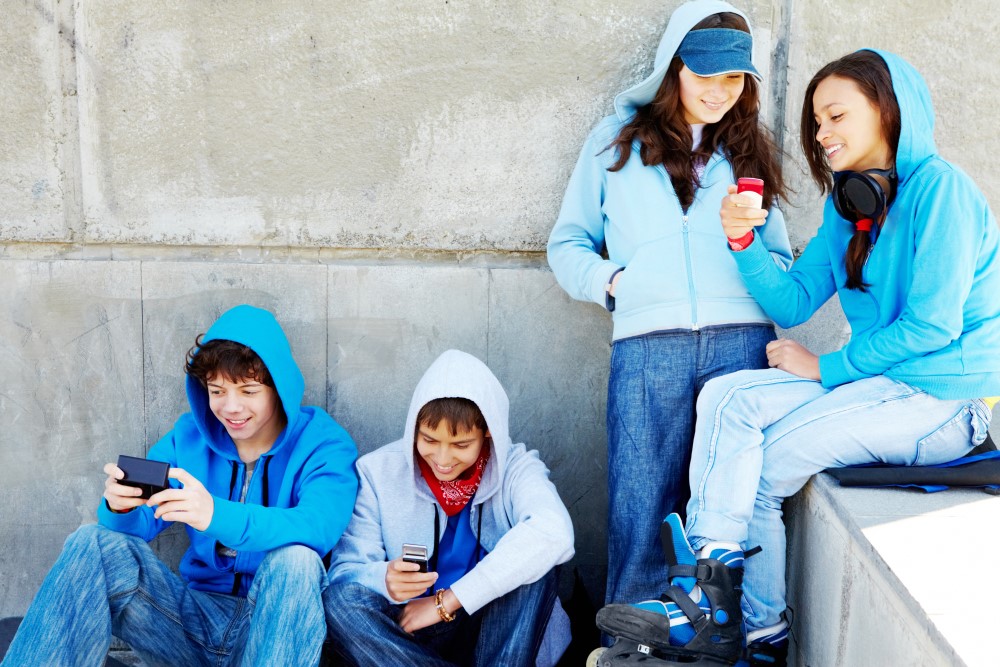 Fore ungdommer med mobiltelefoner sitter i en trapp
