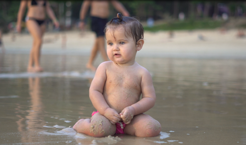 Baby som sitter i vannkanten på offentlig svar.