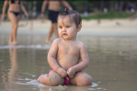 Baby som sitter i vannkanten på offentlig svar.