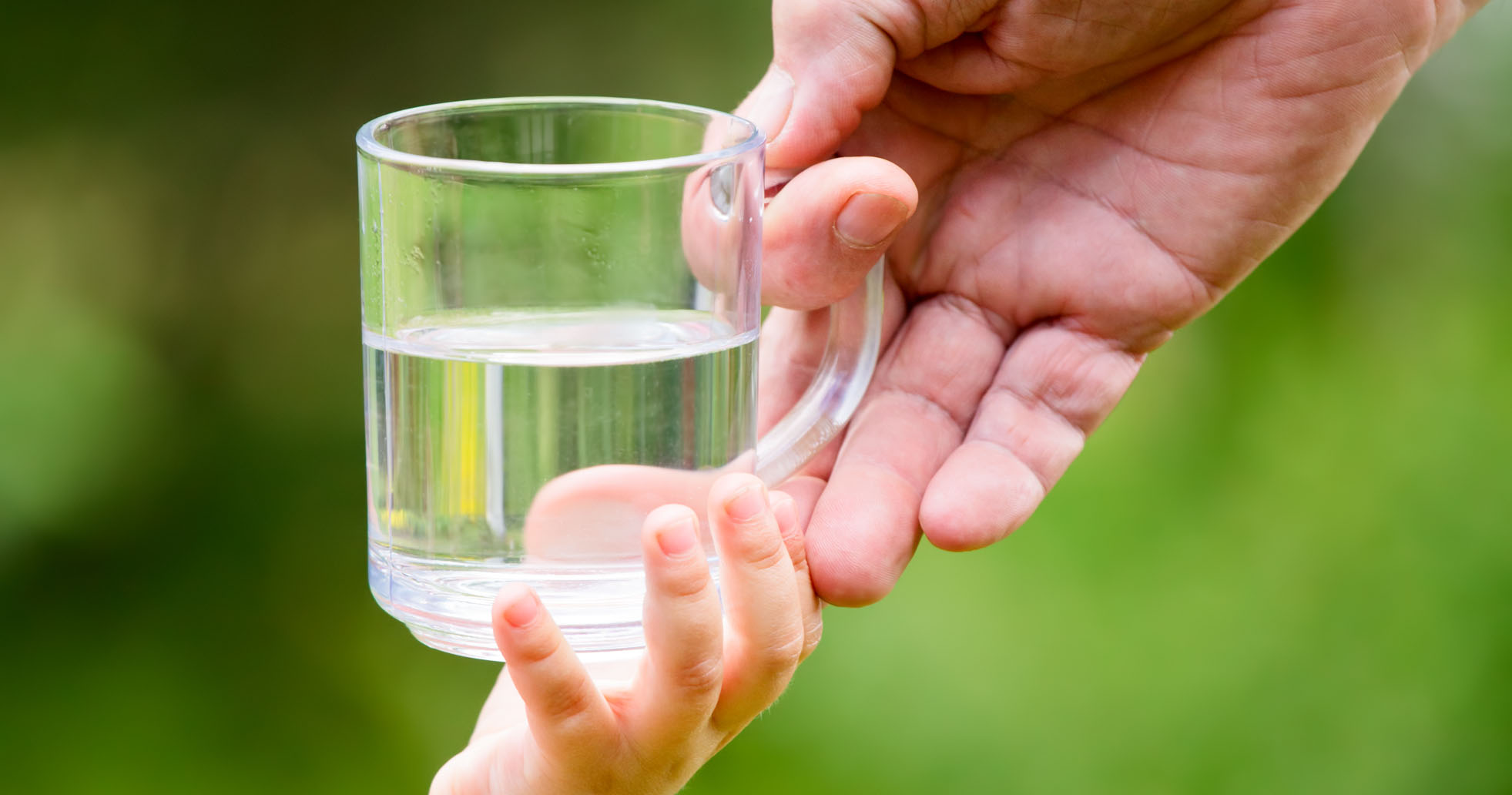 Barn gir et glass med vann til en voksen
