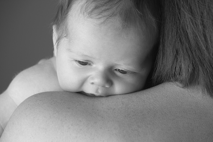 nyfødt baby som holdes av mor på skulderen
